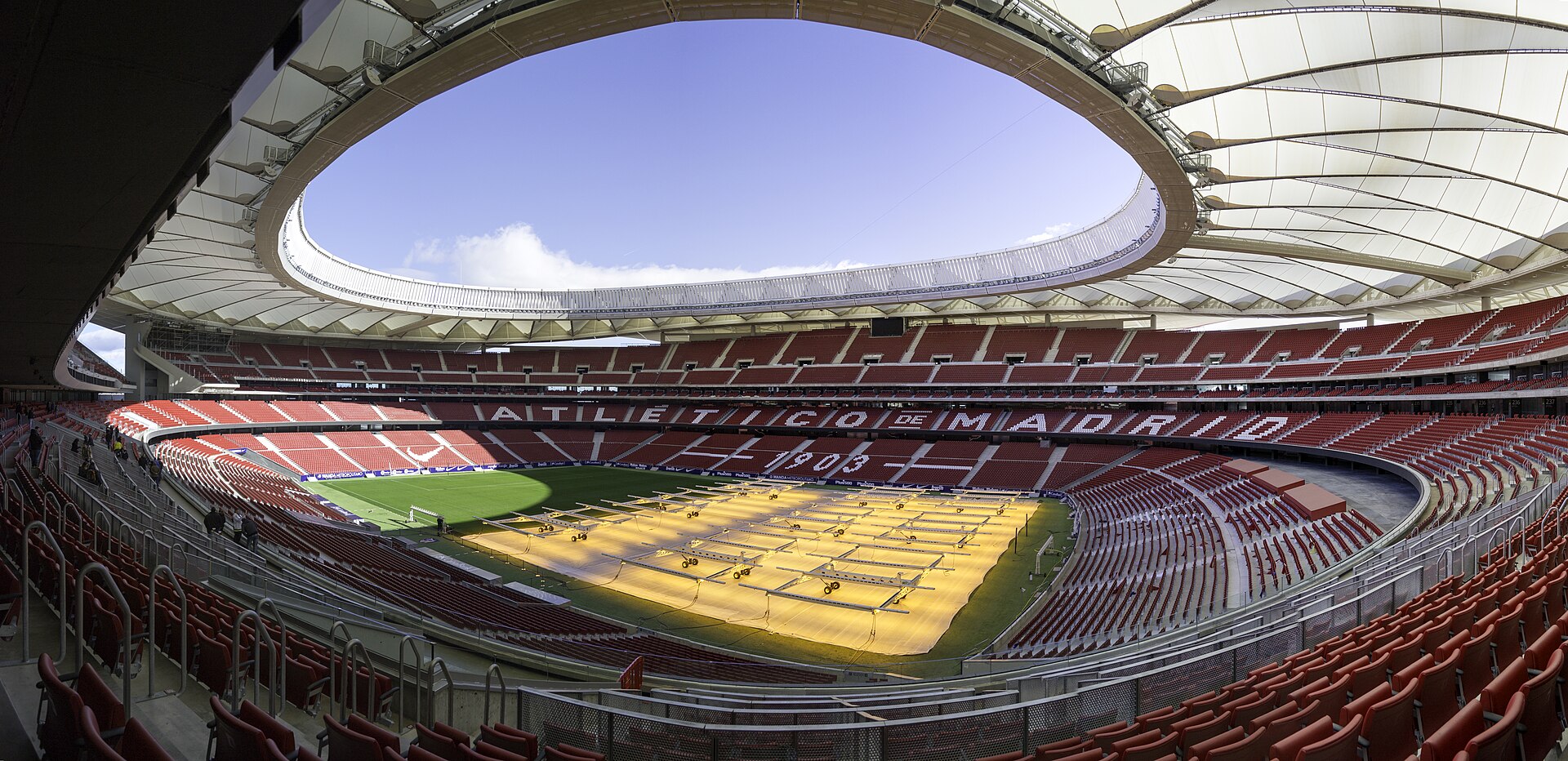 A madridi Metropolitano Stadion üres, piros lelátói és napsütötte játéktere.